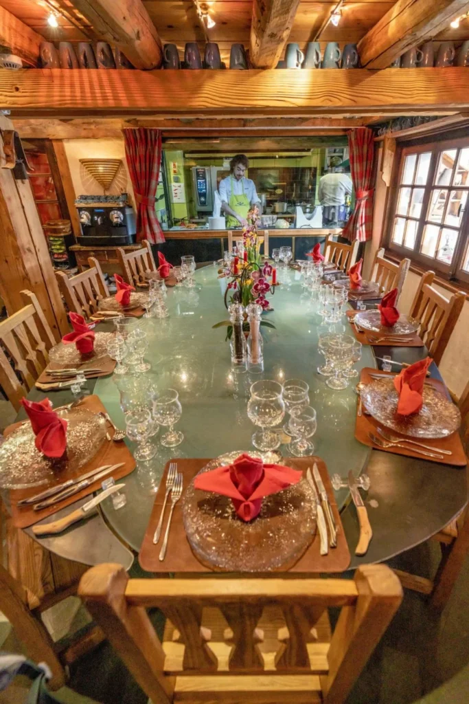 A captivating shot of the exclusive Chef's Table at Alpine Garden Restaurant, showcasing the elegant glass and granite design. The photo captures the dynamic atmosphere of the kitchen in the background, where the Chef and brigade are at work, with the beautifully set table ready for guests.